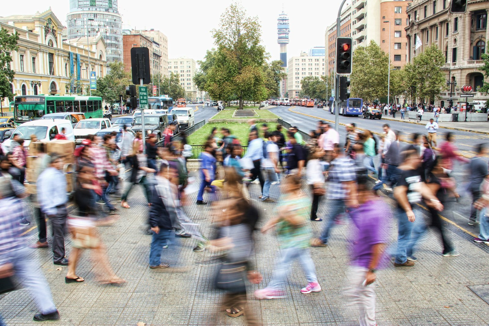 A busy motion-blurred crowd crossing a city street.