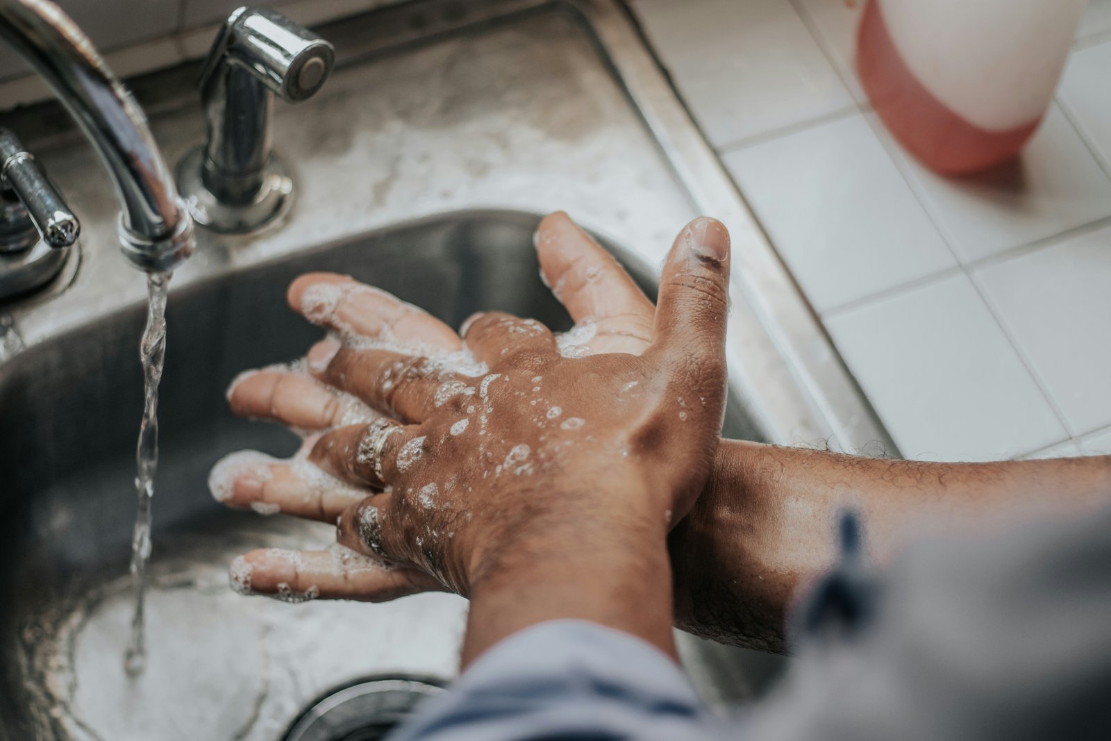 A person washing their soapy hands thoroughly at a sink.