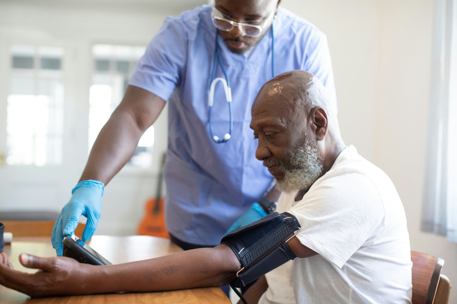A healthcare volunteer checking an elderly patient's blood pressure at a home visit.