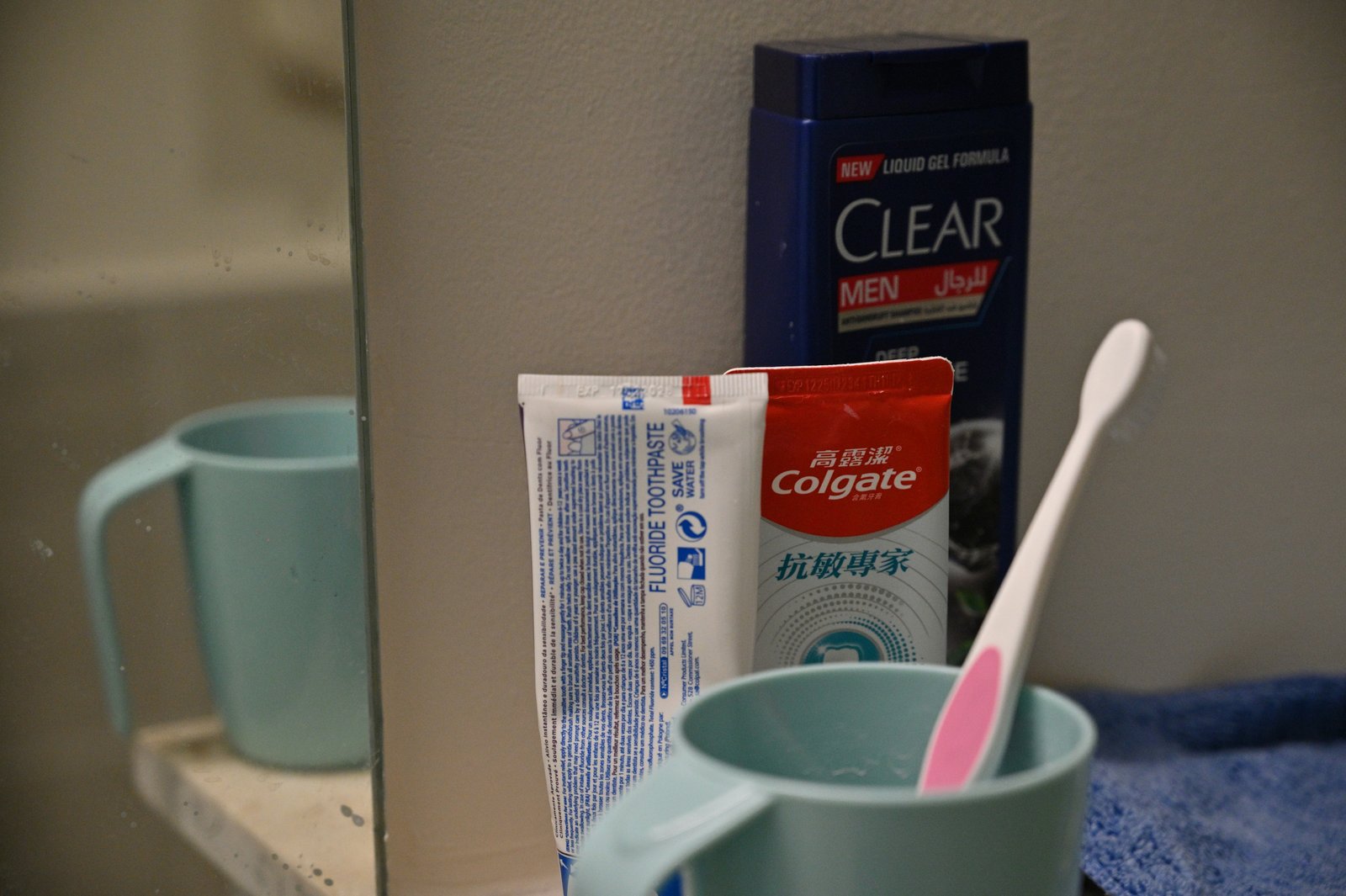 Toothbrush, toothpaste, and shampoo arranged on a bathroom shelf.