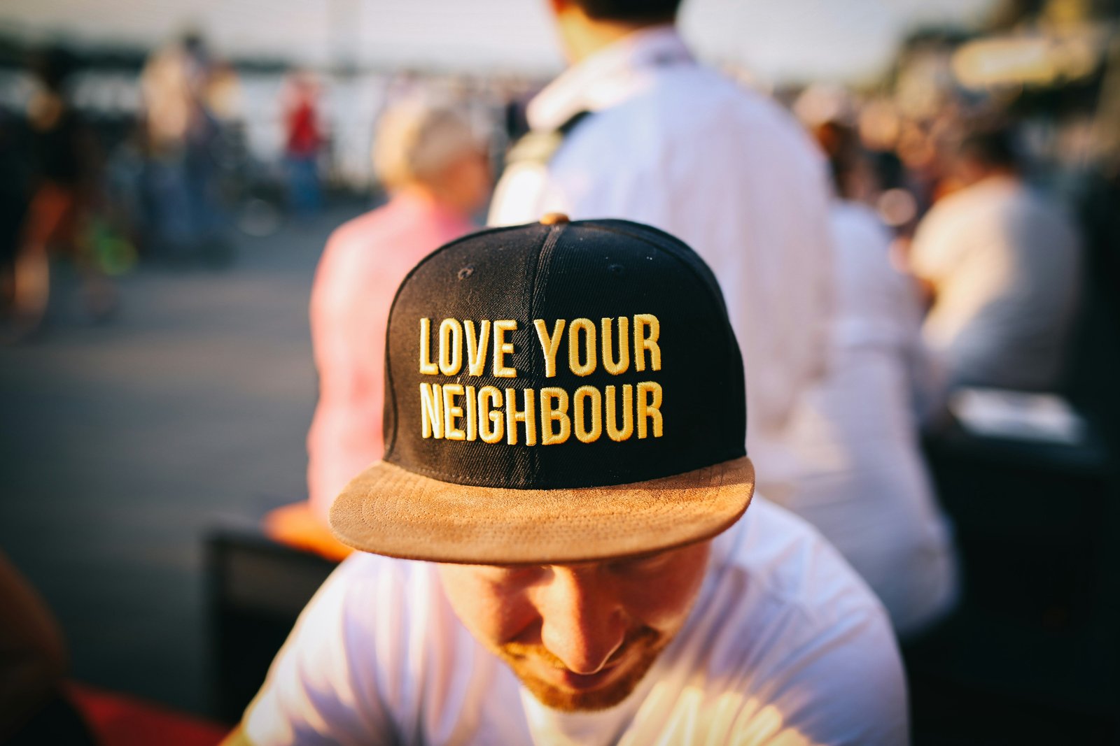 A cap embroidered with the words 'Love Your Neighbour' at an outdoor gathering.