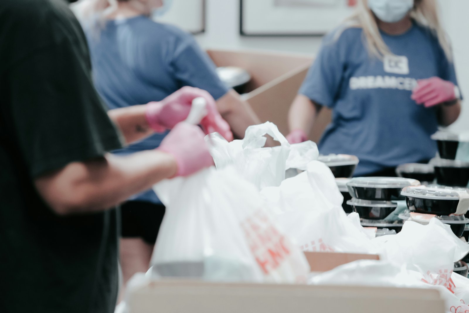 Volunteers packing prepared meal containers into bags for distribution.