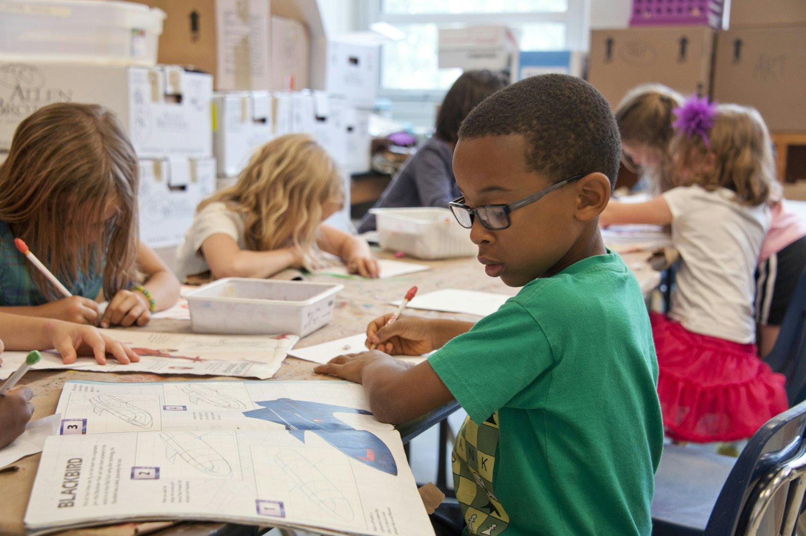 Children working on an art project together at a school table.