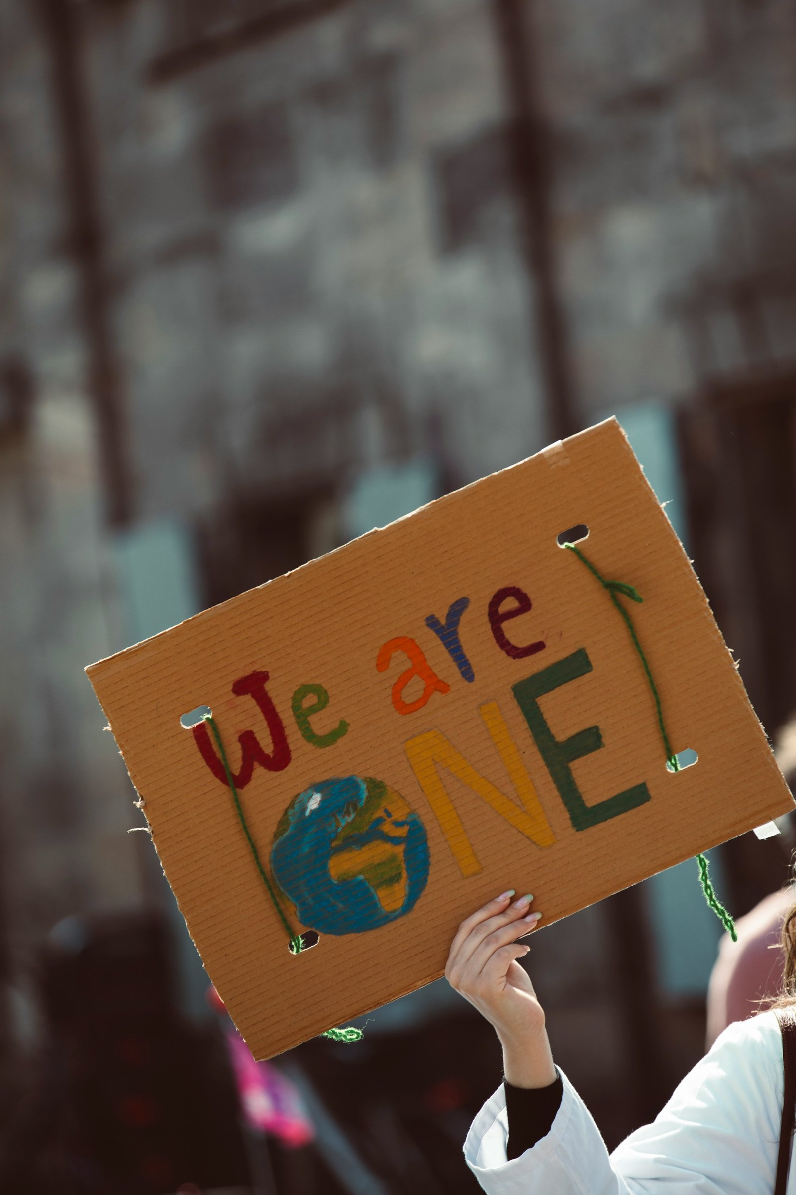 A hand-painted sign reading 'We are ONE' with a small painted globe.